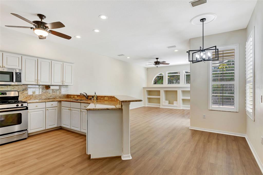 11209 Pine Lilly Place Lakewood Ranch, FL 34202 - Photo 11 of 26 a kitchen with kitchen island a stove a sink and a wooden floors