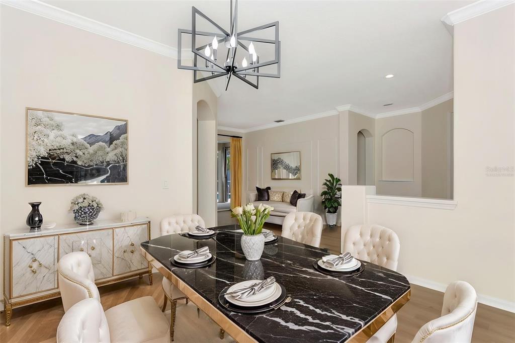 11209 Pine Lilly Place Lakewood Ranch, FL 34202 - Photo 7 of 26 a view of a dining room with furniture a chandelier and wooden floor