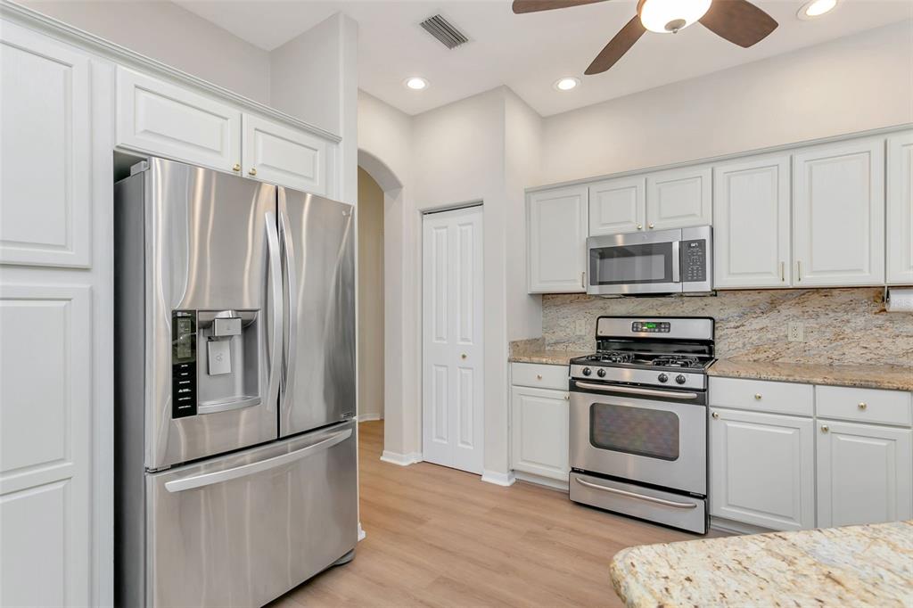 11209 Pine Lilly Place Lakewood Ranch, FL 34202 - Photo 8 of 26 a kitchen with stainless steel appliances granite countertop a refrigerator stove a sink and a white cabinets