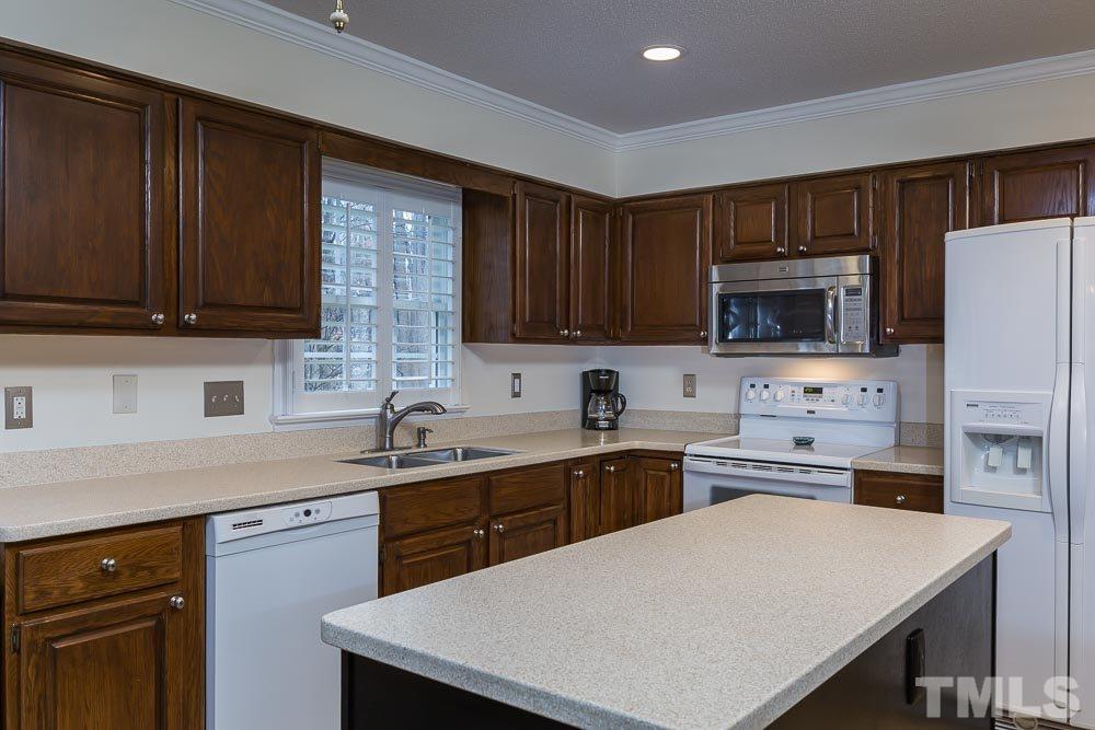 11905 Old Creedmoor Road Raleigh, NC 27613 - Photo 9 of 24 a kitchen with a sink a stove top oven a refrigerator cabinets and a center island