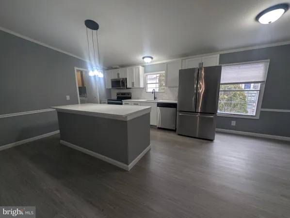 a kitchen with stainless steel appliances a refrigerator sink and wooden floor