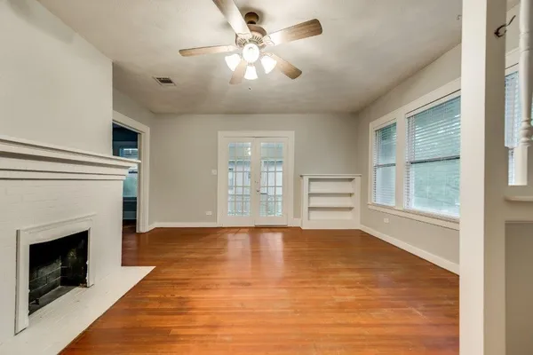 a view of an empty room with chandelier fan and fire place