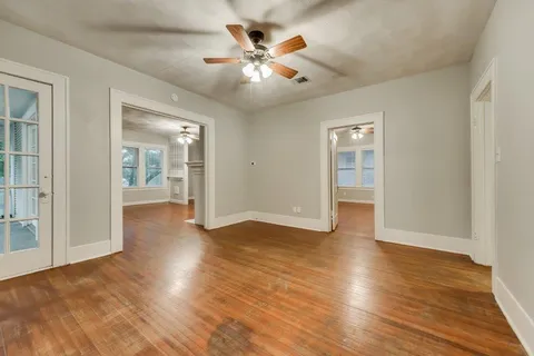 an empty room with wooden floor and ceiling fan