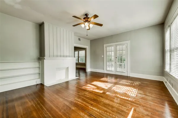 a view of an empty room with a window and wooden floor