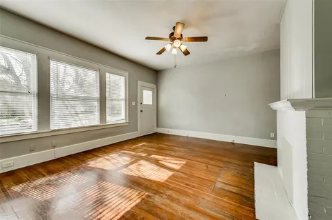 a view of an empty room with window and chandelier fan