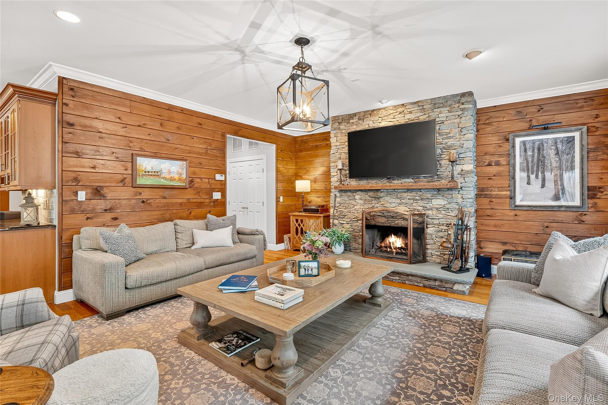 6 Gooler Court Stony Point, NY 10980 - Photo 14 of 50 Living area featuring shiplap walls, a stone fireplace, wood finished floors, a chandelier, and ornamental molding