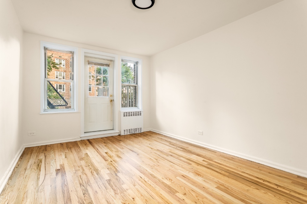 5610 Netherland Avenue, Unit 1G Bronx, NY 10471 - Photo 9 of 17 an empty room with wooden floor and windows
