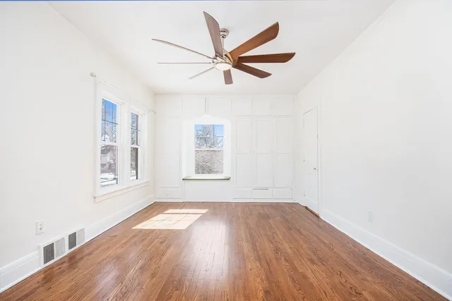 a view of empty room with wooden floor and fan