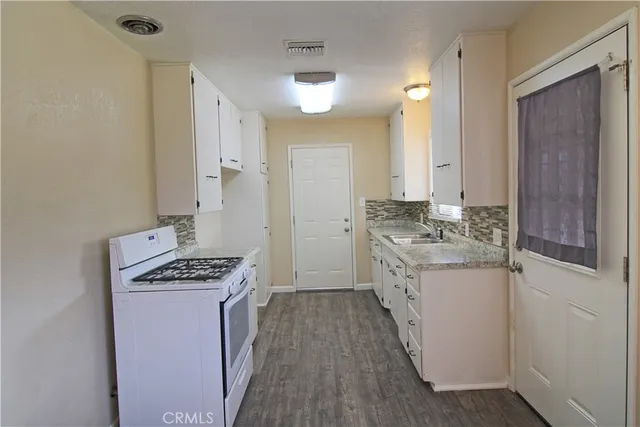 a kitchen with granite countertop a sink stove and cabinets