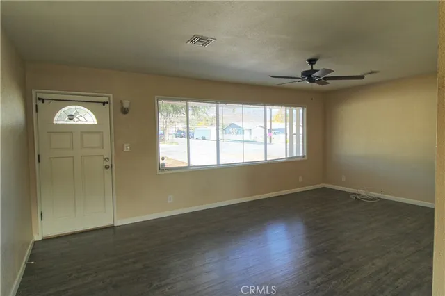 an empty room with wooden floor fan and windows