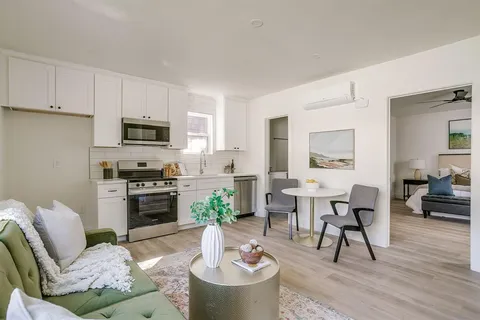 a living room with furniture a fireplace a flat screen tv and kitchen view