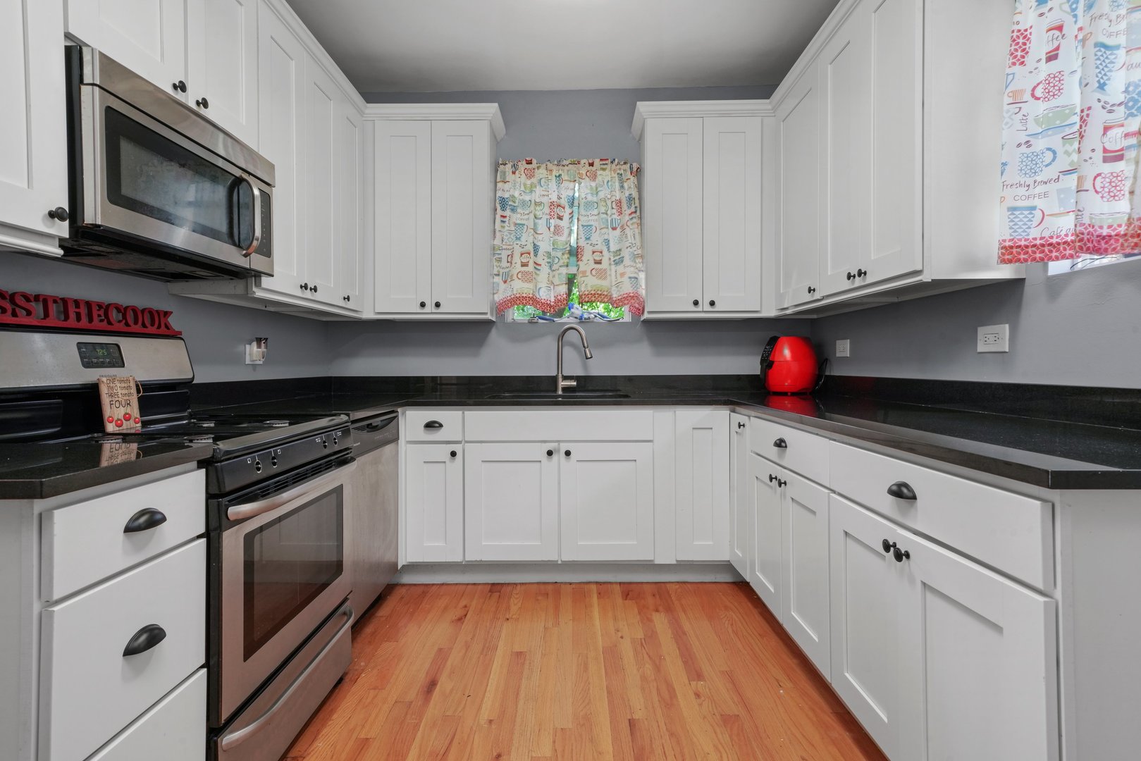 5648 Hawthorne Avenue Berkeley, IL 60163 - Photo 12 of 25 a kitchen with stainless steel appliances granite countertop white cabinets granite counter tops and a wooden floor