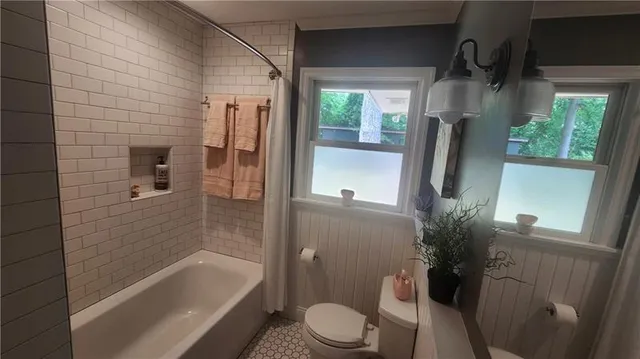 a bathroom with a shower a toilet and a tub