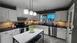 a kitchen with a sink a stove cabinets and a dining room