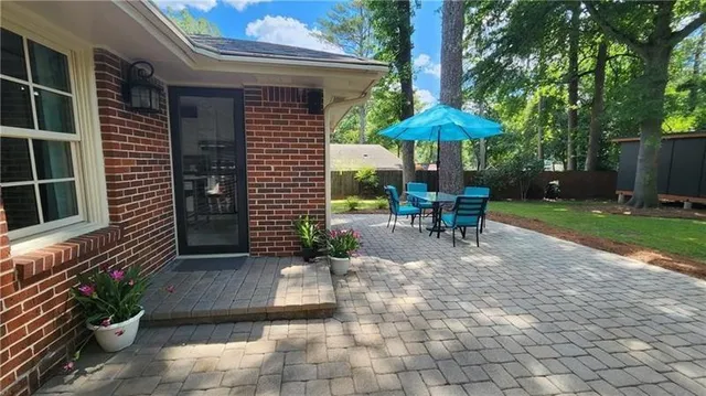 a view of a chairs and table under an umbrella in backyard