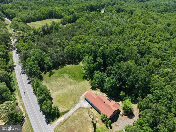 an aerial view of residential house with outdoor space and trees all around