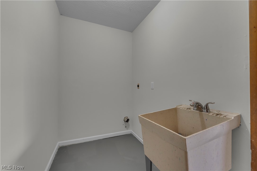 2540 Charney Road University Heights, OH 44118 - Photo 33 of 44 Utility room featuring a built-in wash basin with a chrome faucet, light gray walls, and matching gray flooring