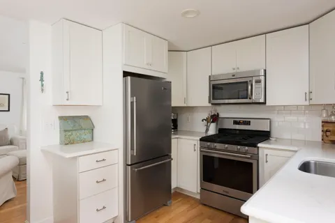 a kitchen with cabinets stainless steel appliances and wooden floor