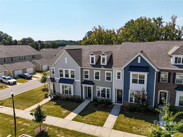 a view of a big house with a big yard plants and large trees