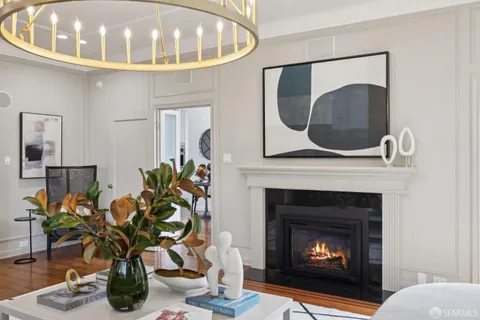 a kitchen with stainless steel appliances a stove a sink dishwasher a refrigerator white cabinets and wooden floor