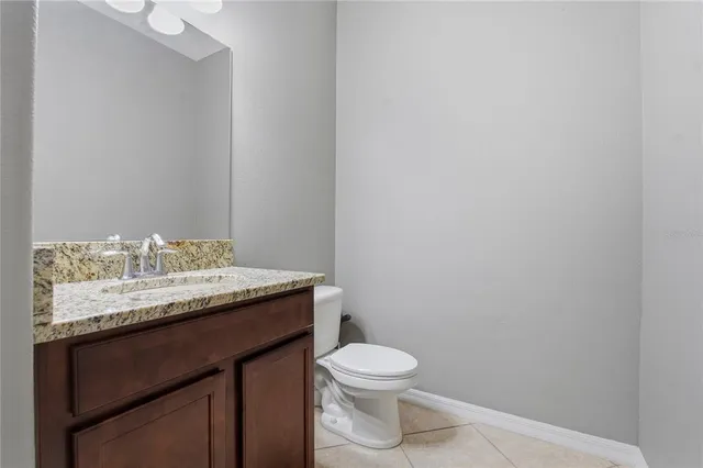 a bathroom with a granite countertop sink and a toilet