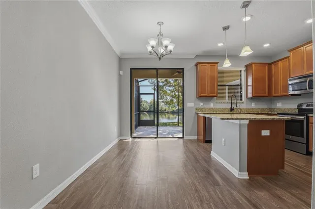a open kitchen with granite countertop a stove top oven a sink and dishwasher with wooden floor