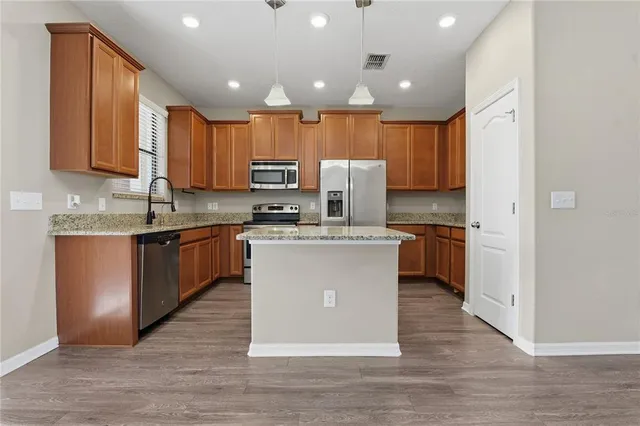 a kitchen with kitchen island wooden cabinets and stainless steel appliances