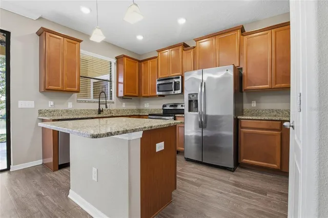a kitchen with stainless steel appliances granite countertop a refrigerator a sink and a microwave