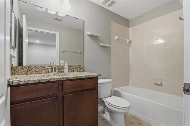 a bathroom with a granite countertop toilet a sink and a bathtub