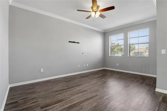 an empty room with wooden floor fan and windows