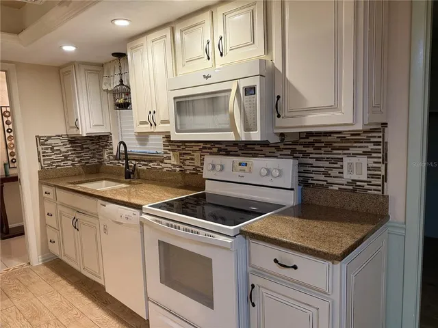 a kitchen with white cabinets sink and stainless steel appliances