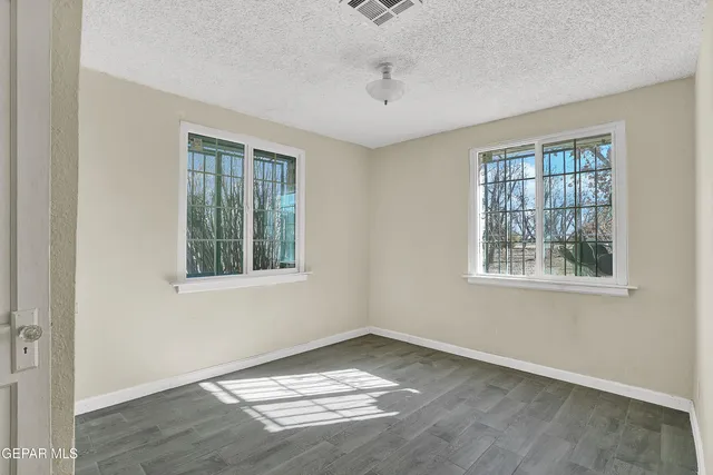 an empty room with wooden floor chandelier fan and windows