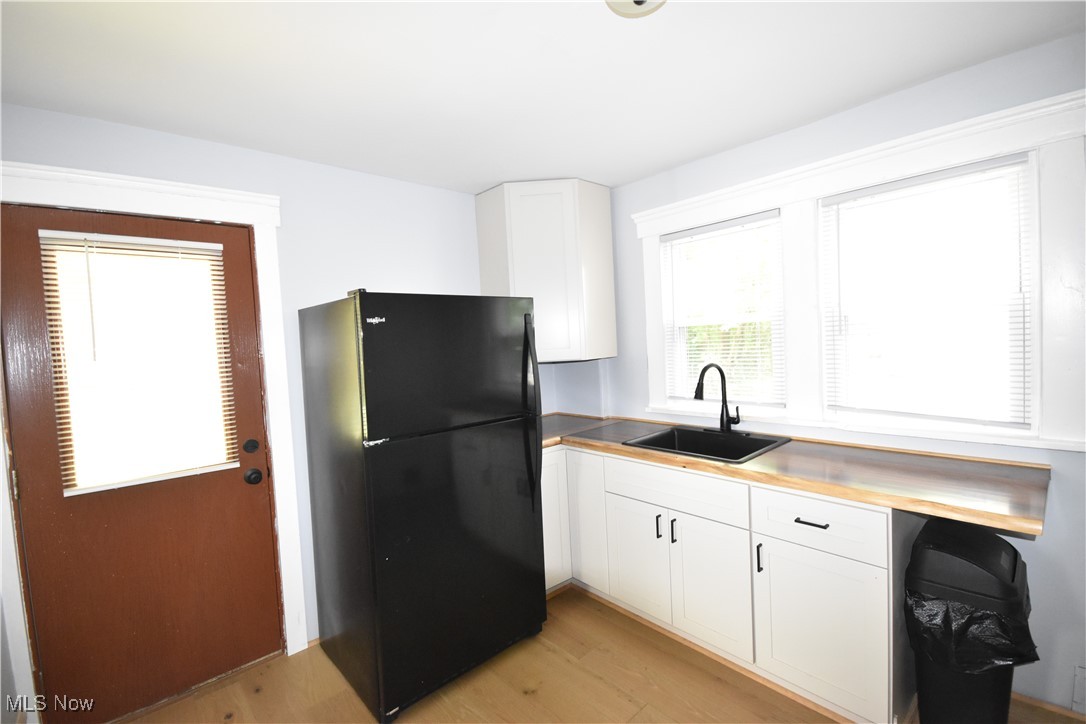 808 West Riddle Avenue Ravenna, OH 44266 - Photo 13 of 28 Kitchen featuring white cabinets, light wood-type flooring, black fridge, and sink