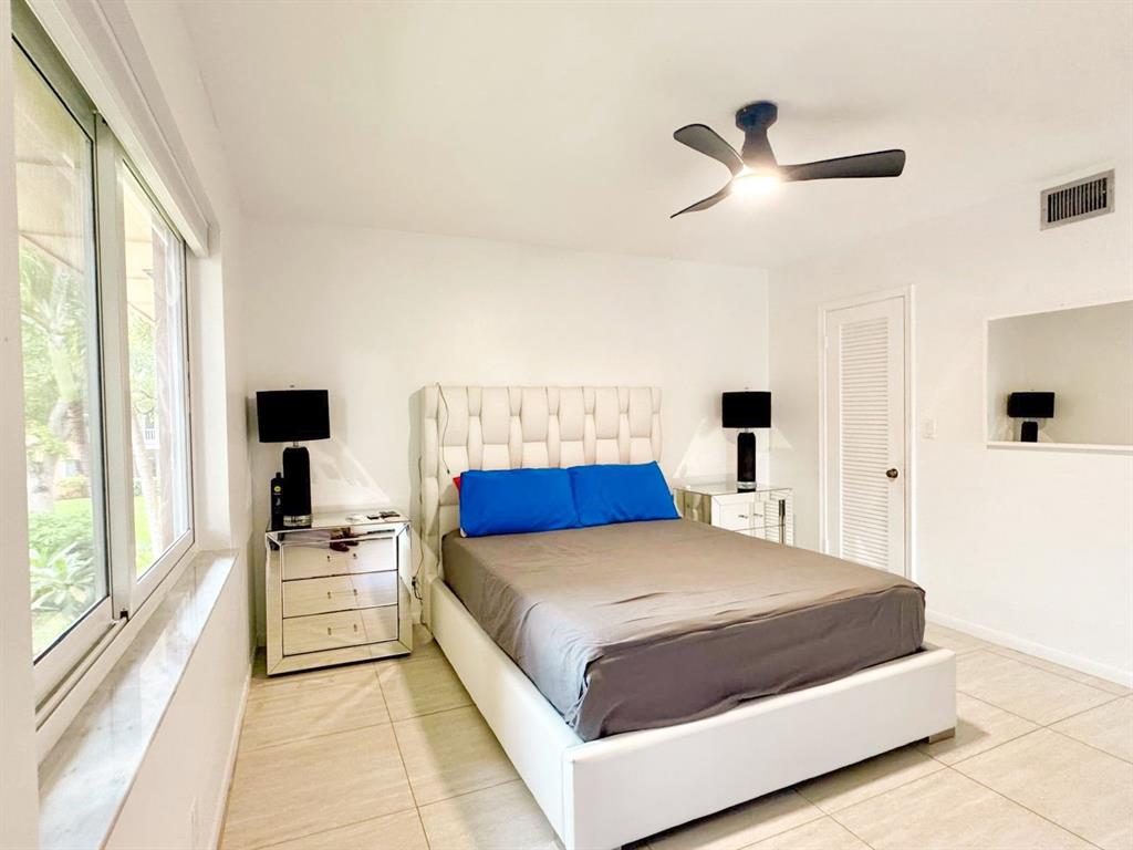 136 Northeast 19th Court, Unit 216F Wilton Manors, FL 33305 - Photo 3 of 26 a bedroom with a large bed and a flat tv screen on dresser