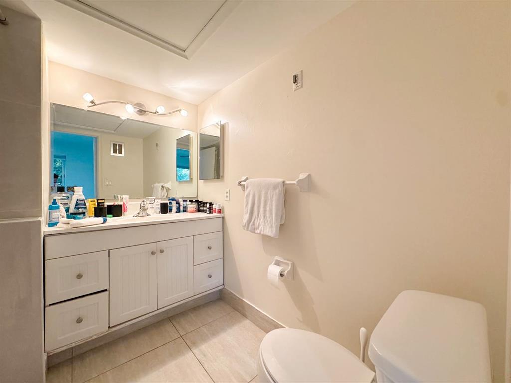 136 Northeast 19th Court, Unit 216F Wilton Manors, FL 33305 - Photo 5 of 26 a spacious bathroom with a toilet sink and mirror