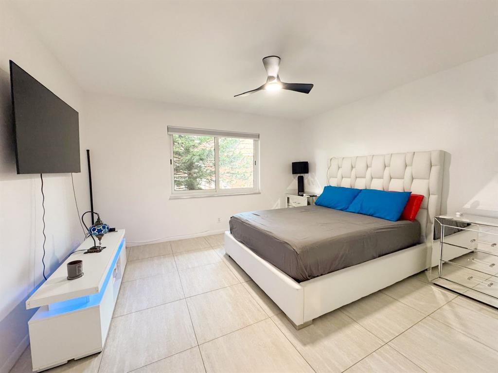 136 Northeast 19th Court, Unit 216F Wilton Manors, FL 33305 - Photo 8 of 26 a bedroom with a bed and a flat screen tv