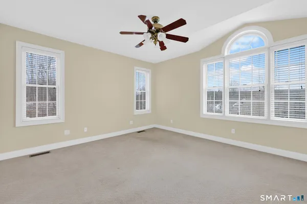 an empty room with windows and ceiling fan