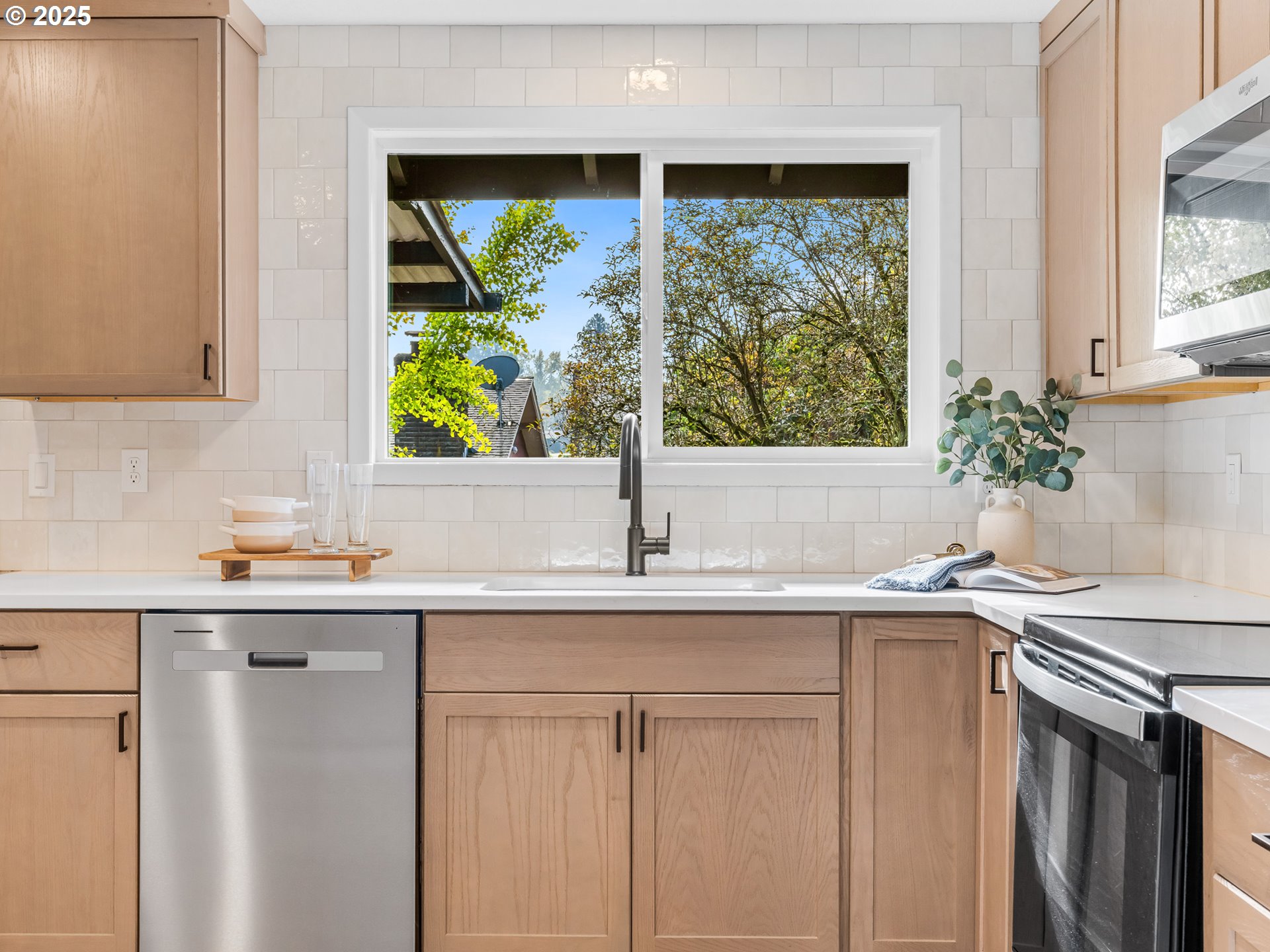 12942 Northeast Morris Street Portland, OR 97230 - Photo 8 of 28 a kitchen with stainless steel appliances white cabinets a sink and a large window