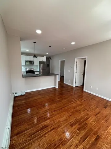 a view of kitchen and empty room with wooden floor