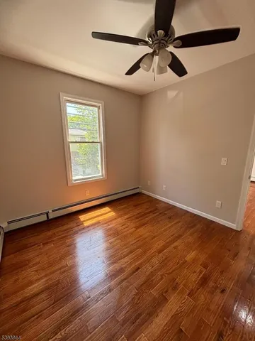 an empty room with wooden floor fan and windows