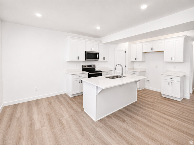 1004 West Paramount Cove South, Unit 315 Ogden, UT 84405 - Photo 28 of 42 Basement ADU kitchen featuring white shaker cabinetry, light-toned wood-finish flooring, recessed lighting, and a kitchen island with an undermount double-basin sink