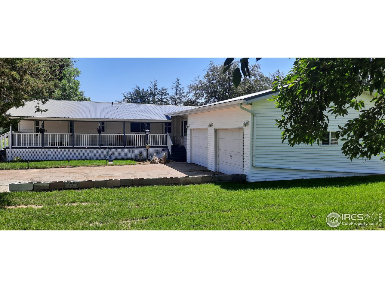 a view of a white house with a big yard and potted plants