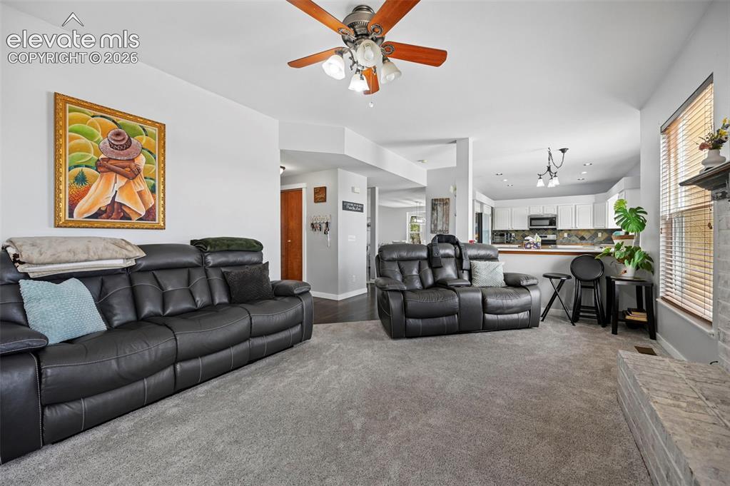 8347 Tibbs Road Peyton, CO 80831 - Photo 4 of 39 Open-concept living space featuring light gray wall paint and matching carpeting