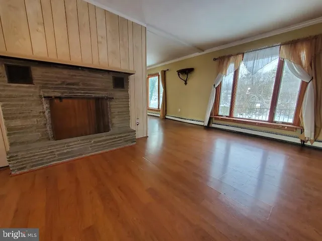 an empty room with wooden floor fireplace and windows