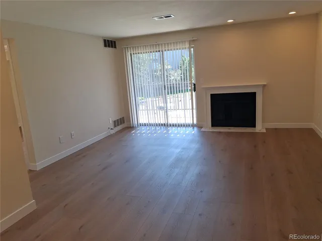 an empty room with wooden floor and a fireplace