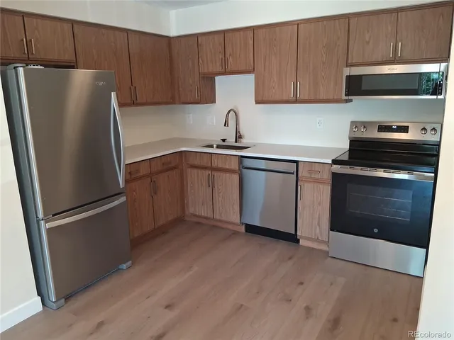 a kitchen with a refrigerator sink and wooden cabinets