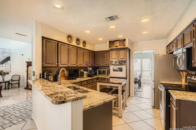 a kitchen with stainless steel appliances granite countertop a sink stove and refrigerator