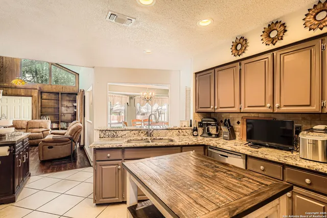 a kitchen with stainless steel appliances granite countertop a stove top oven a sink dishwasher and cabinets with wooden floor