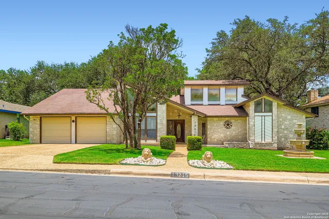 a view of a house with a yard and large tree and plants