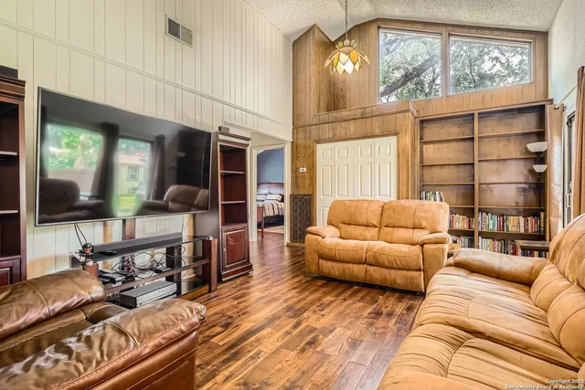 a living room with furniture a flat screen tv and a floor to ceiling window